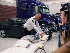 Insp. Max Waddell of the Winnipeg Police Service's organized crime unit moves two large bags of methamphetamine, as drugs are laid out in front of the semi that was allegedly used to transport them from B.C.