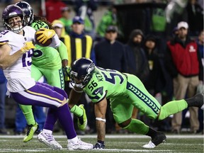 Mychal Kendricks (right) of the Seattle Seahawks reaches out to take down receiver Adam Thielen of the Minnesota Vikings during Monday night’s NFL game at CenturyLink Field in Seattle.