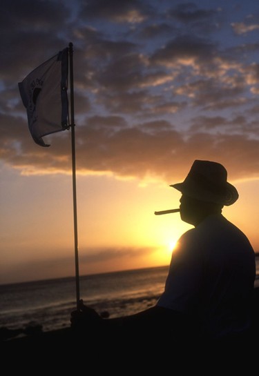 A golfer enjoys a Dominican cigar at sunset on the 5th green at the Teeth of the Dog.