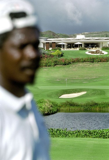 Caddie and clubhouse at the Sandy Lane Country Club's finishing hole.