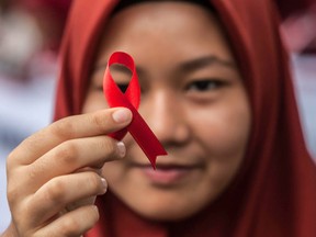 An Indonesian student holds a red ribbon as part of an awareness event on the occasion of World AIDS Day in Medan, North Sumatra province, on December 2, 2018. - World AIDS Day has been observed today since 1988 to raise awareness of the AIDS pandemic.