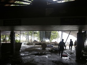 Rescueers walk around a destroyed stage at a beach resort in Tanjung Lesung, Indonesia, Monday, Dec. 24, 2018. Doctors are working to help survivors and rescuers are looking for more victims from a deadly tsunami that smashed into beachside buildings along an Indonesian strait. The waves that swept terrified people into the sea Saturday night followed an eruption on Anak Krakatau, one of the world's most infamous volcanic islands.