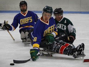 Humboldt Broncos hockey player Ryan Straschnitzki, middle, passes the puck away from Marty Richardson, right, as Broncos teammate Jacob Wassermann follows the play during a sled hockey scrimmage at the Edge Ice Arena in Littleton, Colo., on Nov. 23.