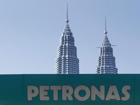 A Petronas gas station signage is pictured against Malaysia's landmark building, Petronas Twin Towers in Kuala Lumpur, Malaysia, Wednesday, March 2, 2016. Natural gas prices in Western Canada are so low that a partner in the country's first LNG export project is shutting off money-losing wells and throttling back its exploration program.