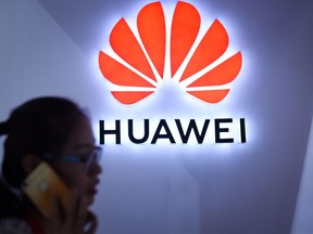 (FILES) In this file photo taken on July 8, 2018 a woman uses her mobile phone in front of a Huawei logo at Beijing International Consumer Electronics Expo in Beijing. - The US is trying to persuade wireless companies and internet providers in allied countries to shun equipment made by Chinese telecom giant Huawei, citing cyber security risks, The Wall Street Journal reported on November 23, 2018.