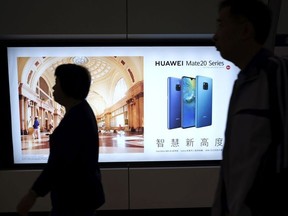 People walk past an advertisement for Huawei at a subway station in Hong Kong Thursday, Dec. 5, 2018. Canadian authorities said Wednesday that they have arrested Huawei's chief financial officer Meng Wanzhou for possible extradition to the United States.
