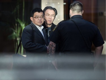Two unidentified men speak with a sheriff while waiting to enter a courtroom to attend a bail hearing for Meng Wanzhou, the chief financial officer of Huawei Technologies, at B.C. Supreme Court in Vancouver, on Dec. 7, 2018.