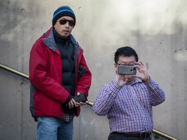 A man takes a photograph with a smartphone while waiting in line to enter a courtroom to attend a bail hearing for Meng Wanzhou, the chief financial officer of Huawei Technologies, at B.C. Supreme Court in Vancouver, on Dec. 7, 2018.