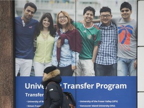 A man walks past a poster for a college in downtown Vancouver that caters to international students.