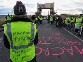 A Yellow vests (Gilets jaunes) protester with the words written of the back of her vest that read, ' Macron (referring to the French President) traitor, the people are hungry' blocks the road leading to the Frontignan oil depot in the south of France, as they demonstrate against the rise in fuel prices and the cost of living on December 3, 2018.