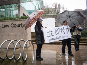 Supporters hold a sign outside B.C. Supreme Court during the third day of a bail hearing for Meng Wanzhou, the chief financial officer of Huawei Technologies, in Vancouver, on Dec. 11, 2018.