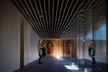 A woman takes a photograph of the trees outside as a First Nations Dogfish Mask by Haida artist Robert Davidson is displayed at the Audain Art Museum in Whistler.