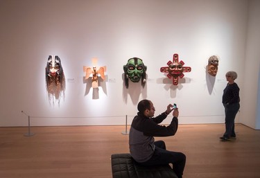 A man takes a photograph as a woman views First Nations masks at the Audain Art Museum in Whistler.