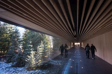 People walk down a long hallway with a view of the outdoors at the Audain Art Museum in Whistler.