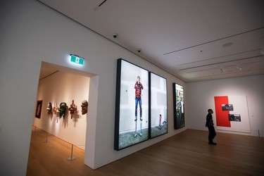 A man views photographs as First Nations masks are displayed in the adjacent room at the Audain Art Museum in Whistler.