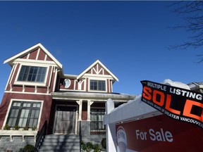 A real estate sold sign is shown outside a house in Vancouver.