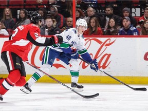 Dylan DeMelo of the Ottawa Senators defends against Elias Pettersson, who netted his first NHL hat trick in the win.