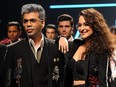 Indian Bollywood film director Karan Johar (L) and actress Sonakshi Sinha (R) showcase creations by designer Falguni Shane Peacock at the Lakmé Fashion Week (LFW) Summer Resort 2018 in Mumbai on February 2, 2018.