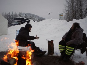 Alexander Joseph, right, and another supporter look on as an RCMP prepares to lane as they joins supporters of the Unist'ot'en camp and Wet'suwet'en First Nation gather at a camp fire off a logging road near Houston on Wednesday, Jan. 9, 2019.