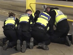 Police restraining a man after he stabbed three people at Victoria Station in Manchester, England, late Monday Dec. 31, 2018. Two commuters - a man and woman in their 50s - were taken to hospital with knife injuries and a British Transport Police (BTP) officer was stabbed in the shoulder. Police said a man was arrested on suspicion of attempted murder and remains in custody.