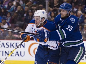 Alex Edler and Buffalo Sabres Sam Reinhart eye the puck as goalie Thatcher Demko makes a glove save in the second period of the Vancouver Canucks' 4-3 victory at Rogers Arena Friday night.