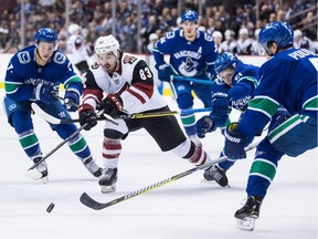 Conor Garland of the Arizona Coyotes skates with the puck past Vancouver Canucks' Nikolay Goldobin, back left, Troy Stecher, back right, and Derrick Pouliot, front right, during Thursday's NHL game in Vancouver.