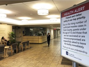 A sign prohibiting all children under 12 and unvaccinated adults stands at the entrance to PeaceHealth Southwest Medical Center in Vancouver, Wash., on Friday. B.C. residents are also been warned about the outbreak.