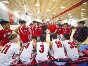 St. Thomas More players and coaches huddle during a timeout while playing McNair Secondary in high school boys' basketball action in Burnaby.