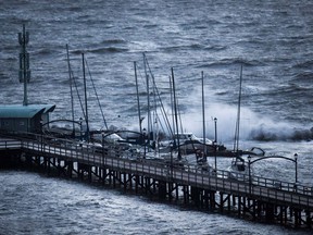 Boats are battered by waves at the end of the White Rock Pier that was severely damaged during a windstorm, in White Rock, B.C., on December 20, 2018. A single repair in the wake of a hurricane-force windstorm that tore across southern British Columbia last month is now estimated to cost as much as $16 million. The City of White Rock's engineering department has sent a report to council estimating repairs to the White Rock pier south of Vancouver could cost between $14- and $16 million, while immediate fixes could tally nearly $5 million.