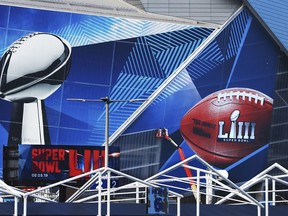 In this Jan. 17, 2019 photo, workers use a lift to install a Super Bowl 53 wrap on the outside of Mercedes-Benz Stadium as it is transformed for the big NFL football game in Atlanta. Kraft Heinz' frozen-food brand Devour is trying to make waves during its Super Bowl debut with an ad taking a humorous jab at one man's "frozen food porn addiction." Super Bowl ads have long used raunchiness and sex stand out during the Super Bowl, advertising's biggest stage. But the approach runs the risk of offending the audience.