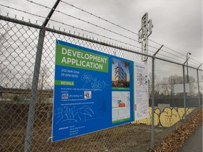 Development sign for an office building at Great Northern Way and Clark Avenue, with the East Van Cross public art sculpture in the background.