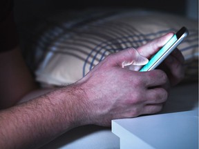 FILE PHOTO: Man using smartphone in bed late, in the middle of the night.