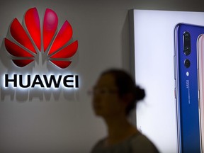 FILE - In this July 4, 2018, file photo, a shopper walks past a Huawei store at a shopping mall in Beijing. Canada's national game _ brought to you by China's Huawei. As a feud deepens between Beijing and Ottawa over the telecom giant, the company's sponsorship of the flagship "Hockey Night in Canada" broadcast raised questions about its involvement in a beloved national institution.