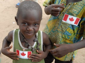 Children in Thiès, Senegal, display Canadian flag stickers and a pin as part of a project run by a Ottawa-based aid group.