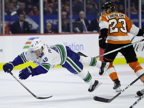 Elias Pettersson of the Vancouver Canucks is tripped by Philadelphia Flyers' Oskar Lindblom during NHL action earlier this month in Philadelphia.