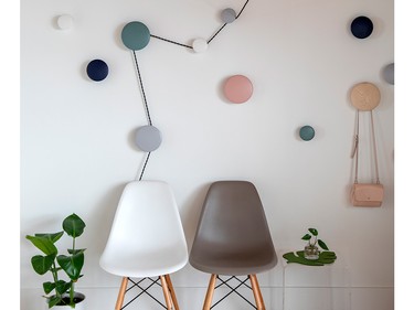 Grey and white mid-century dining chairs add a sleek touch, while wall art does double duty as hanging storage space.