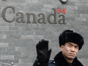 A guard attempts to block photos from being taken outside the Canadian embassy in Beijing on Jan. 27, 2019.
