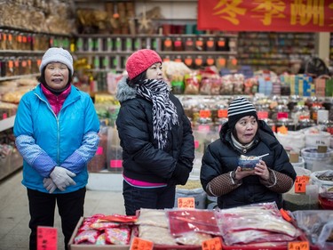 Workers at a traditional herb shop watch the Chinese New Year Parade in Vancouver on Sunday, Feb. 10, 2019. More than 3,000 people participated in the parade according to organizers and more than 100,000 spectators were expected to line the parade route.