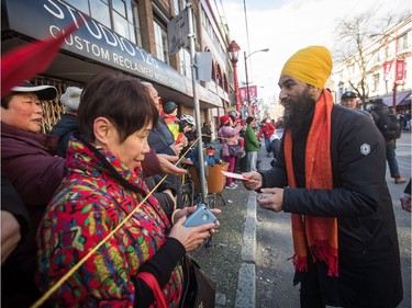 NDP Leader Jagmeet Singh, right, ands out lucky red envelopes while participating in the Chinese New Year Parade in Vancouver on Sunday, Feb. 10, 2019. More than 3,000 people participated in the parade according to organizers and more than 100,000 spectators were expected to line the parade route.