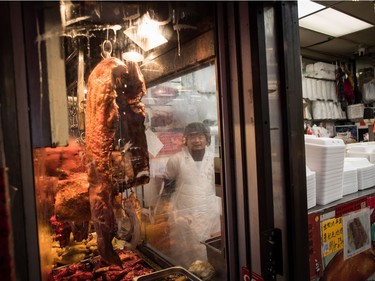 Hong Chou watches the Chinese New Year Parade while working at a barbecue shop in Vancouver on Sunday, Feb. 10, 2019. More than 3,000 people participated in the parade according to organizers and more than 100,000 spectators were expected to line the parade route.