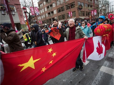 People carry Chinese and Canadian flags while marching in the Chinese New Year Parade in Vancouver on Sunday, Feb. 10, 2019. More than 3,000 people participated in the parade according to organizers and more than 100,000 spectators were expected to line the parade route.