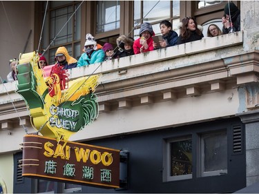 People watch the Chinese New Year Parade from the balcony of a building in Chinatown in Vancouver on Sunday, Feb. 10, 2019.