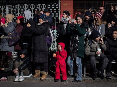 A young girl eats an apple as she and others watch the Chinese New Year Parade in Vancouver on Sunday, Feb. 10, 2019. More than 3,000 people participated in the parade according to organizers and more than 100,000 spectators were expected to line the parade route.