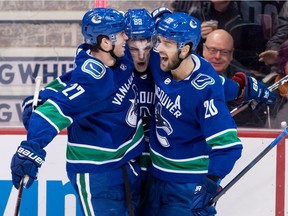 Vancouver Canucks' Ben Hutton, left, and Brandon Sutter, right, celebrate Adam Gaudette's third-period goal Thursday against the Arizona Coyotes at Rogers Arena.