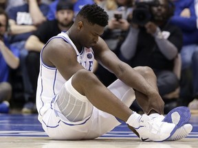 Duke's Zion Williamson sits on the floor following a injury during the first half of an NCAA college basketball game against North Carolina in Durham, N.C., Wednesday, Feb. 20, 2019.