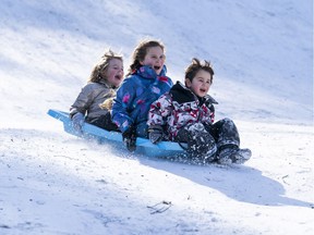 (right to left)  Sam Wozny, Isabella Wozny and Lily Greer take advantage of a snow day by going sledding at QE Park in Vancouver, BC.