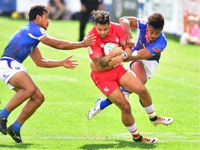 Mike Fuailefau of Canada holds onto the ball under pressure from Joe Perez (R) and Tila Meaoli (L) of Samoa during their pool match on day two of the USA Sevens Rugby tournament in Las Vegas, Nevada on March 2, 2019.