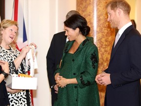 A pregnant Meghan, Duchess of Sussex, and Britain's Prince Harry, Duke of Sussex (right), react as they are presented with baby gifts by Canadian High Commissioner to the United Kingdom Janice Charette (left) at Canada House, the offices of the High Commission of Canada in the United Kingdom, during an event to mark Commonwealth Day in London on March 11, 2019.