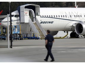 A worker walks next to a Boeing 737 MAX 8 airplane parked at Boeing Field in Seattle on March 14, 2019.