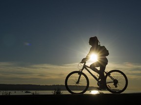A cyclist rides along the seawall at English Bay in the evening sun on March 19 2019.